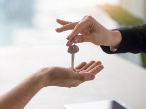 Photo of a key being passed from one hand to another